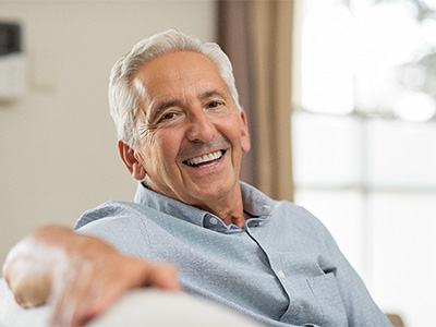 Senior man sitting on couch and smiling