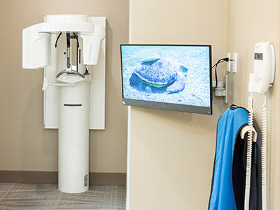 CT cone beam scanner next to computer monitor against white wall in corner