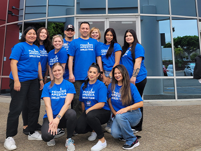 Smiling dental team members wearing matching tee shirts for Feeding America