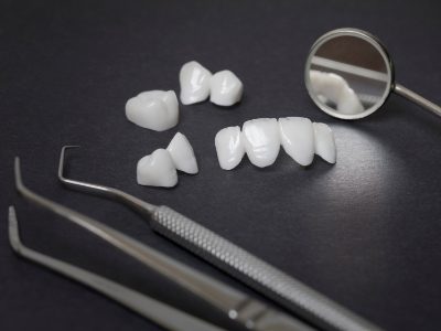 Several dental crowns and veneers resting on tray with dental mirror