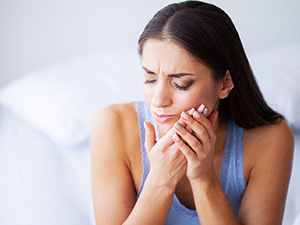 Woman rubbing her jaw due to discomfort