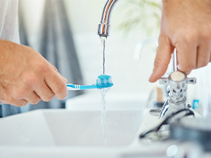 Using sink to rinse off a toothbrush