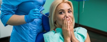Young dental patient covering her mouth with her hands