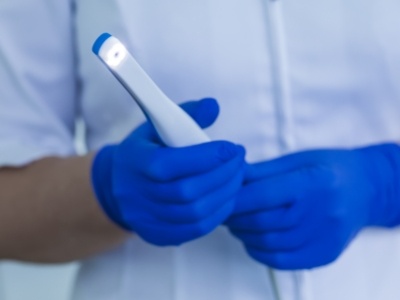 Two gloved hands holding a thin white intraoral camera