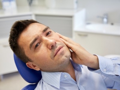 Man holding his cheek in pain while visiting emergency dentist in Encinitas
