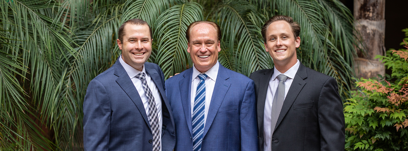 Three smiling Encinitas California dentists wearing suits with ferns in background