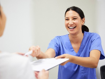 Dental assistant smiling while handing patient form