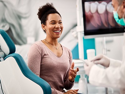 Dentist discussing cost with female patient in treatment chair