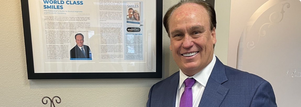 Encinitas dentist Doctor Greg McElroy smiling next to framed article about him