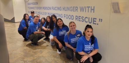 Dental team in hallway wearing matching blue Feeding America tee shirts