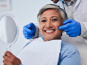 Woman smiling while holding handheld mirror