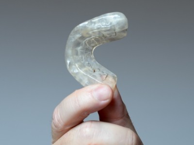 Hand holding a white nightguard for bruxism