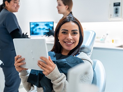 Woman smiling while holding mirror in treatment chair