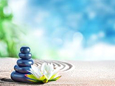 Stack of stones and a flower on a sandy surface